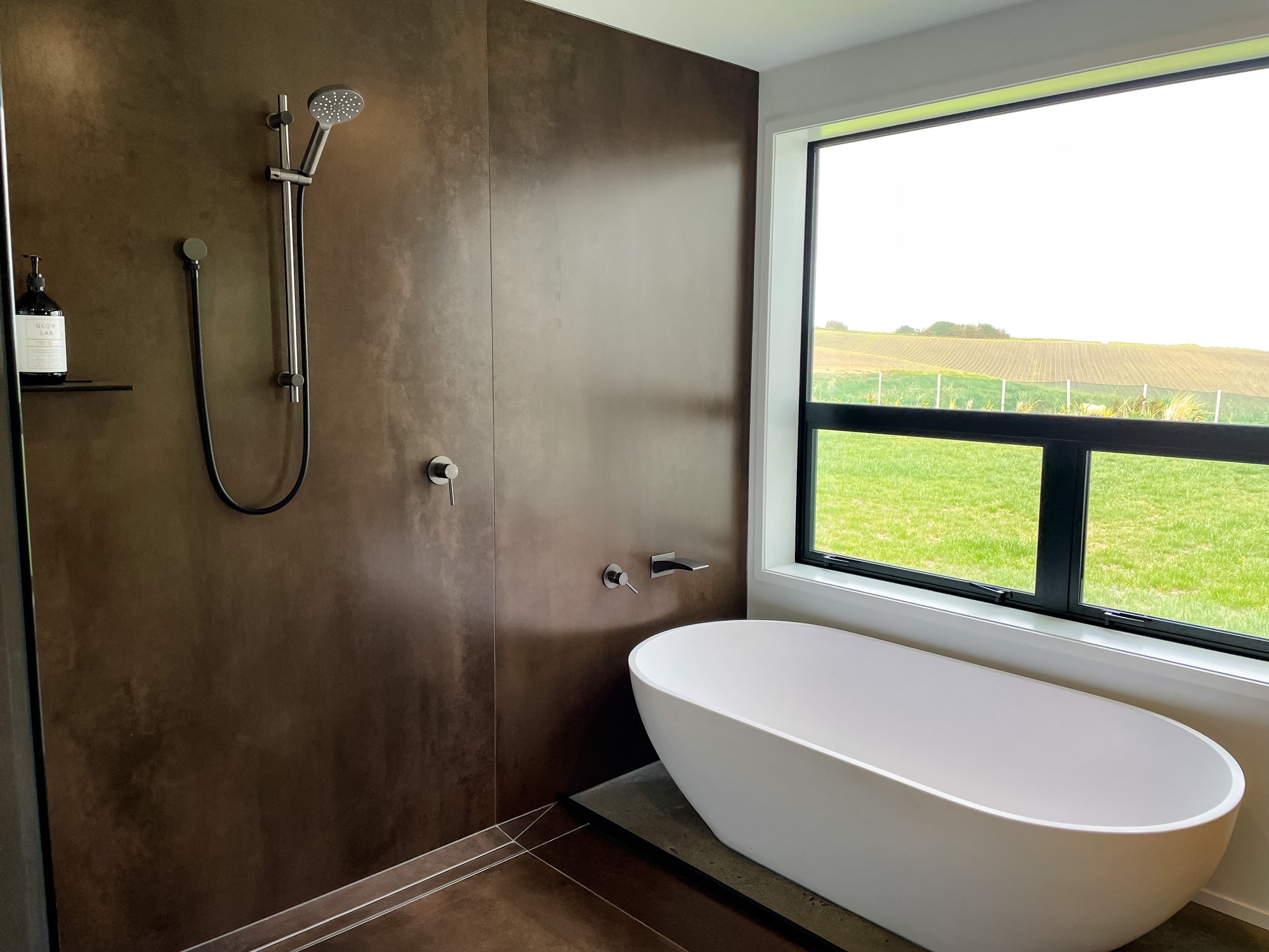 Modern bathroom with freestanding bathtub and wooden shower wall.