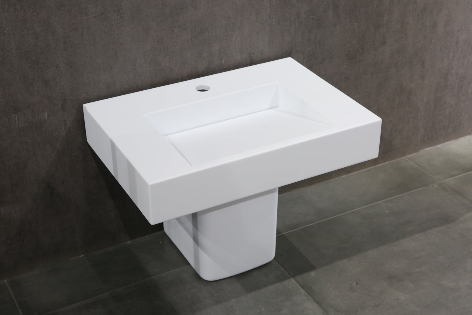 A wall-hung stone basin with a white finish, designed for easy accessibility in healthcare settings.
